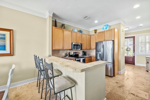 kitchen with kitchen peninsula, appliances with stainless steel finishes, backsplash, and ornamental molding