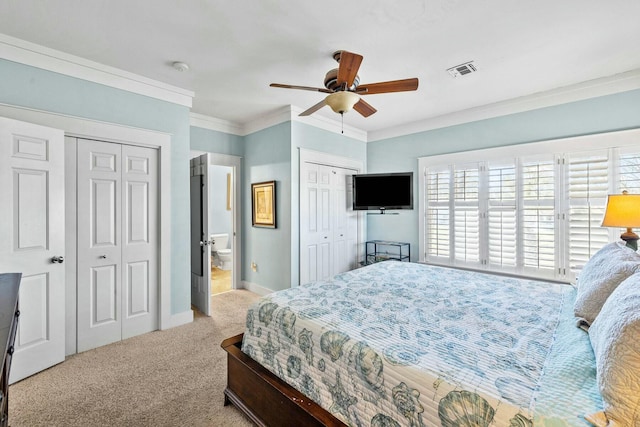 carpeted bedroom with connected bathroom, ceiling fan, two closets, and ornamental molding