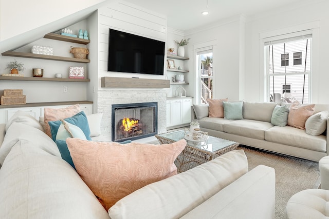 living room featuring a stone fireplace and crown molding