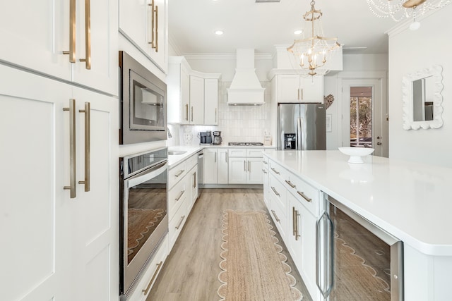 kitchen featuring white cabinets, premium range hood, stainless steel appliances, and beverage cooler