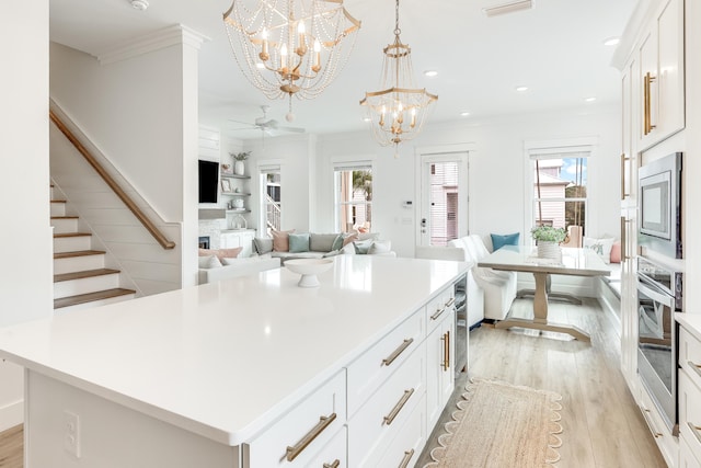 kitchen with a center island, stainless steel appliances, pendant lighting, a fireplace, and white cabinets