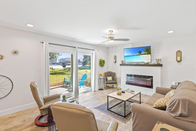 living room with a large fireplace, ceiling fan, and light hardwood / wood-style flooring