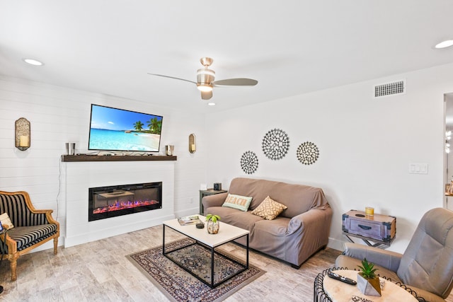 living room featuring a fireplace, light hardwood / wood-style floors, and ceiling fan