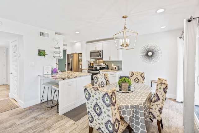 dining room with light hardwood / wood-style floors and a notable chandelier