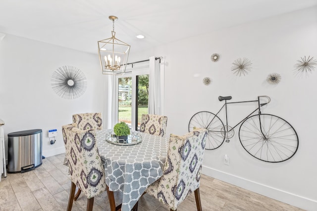 dining space with light hardwood / wood-style floors and an inviting chandelier