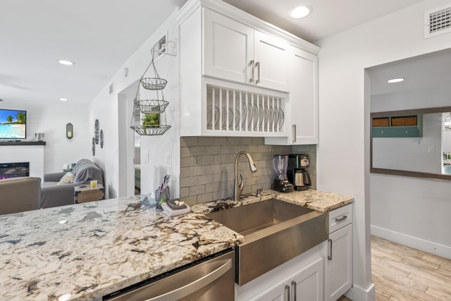 kitchen featuring dishwasher, sink, decorative backsplash, light hardwood / wood-style floors, and white cabinetry