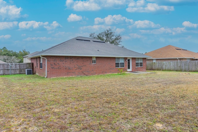 rear view of property with a yard and central air condition unit