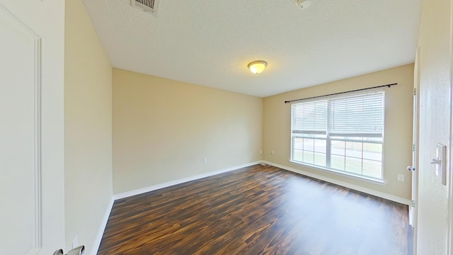 empty room with dark hardwood / wood-style flooring and a textured ceiling