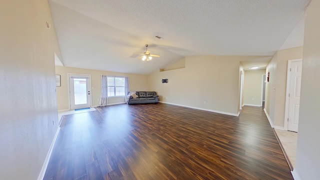 unfurnished living room with a textured ceiling, ceiling fan, dark hardwood / wood-style floors, and lofted ceiling