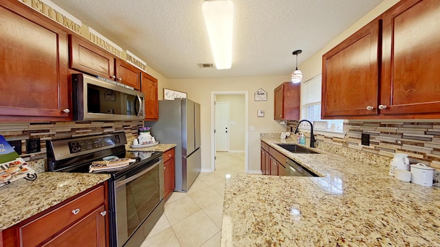 kitchen featuring light stone countertops, tasteful backsplash, stainless steel appliances, sink, and pendant lighting