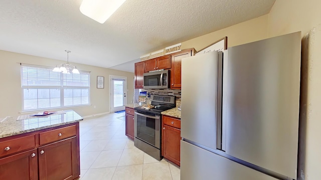 kitchen with pendant lighting, an inviting chandelier, decorative backsplash, appliances with stainless steel finishes, and light stone counters