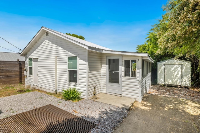 back of house with a storage unit and a patio