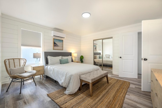 bedroom with a wall unit AC, wood walls, and hardwood / wood-style flooring