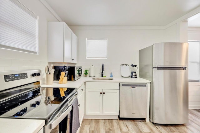 kitchen with white cabinets, light hardwood / wood-style floors, sink, and stainless steel appliances