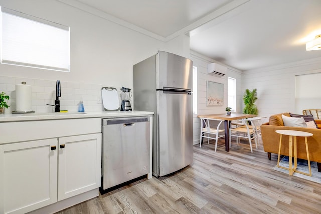 kitchen featuring a wall mounted air conditioner, sink, light hardwood / wood-style floors, white cabinetry, and stainless steel appliances