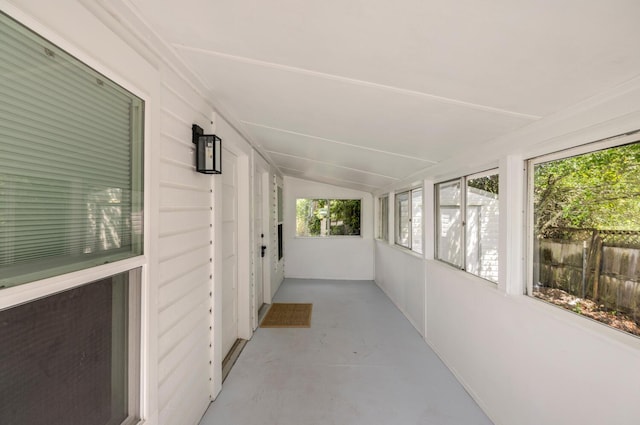 unfurnished sunroom featuring vaulted ceiling and plenty of natural light