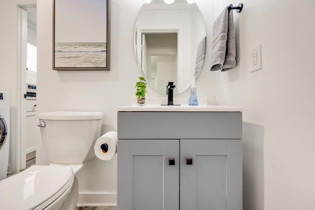 bathroom featuring vanity, stacked washing maching and dryer, and toilet