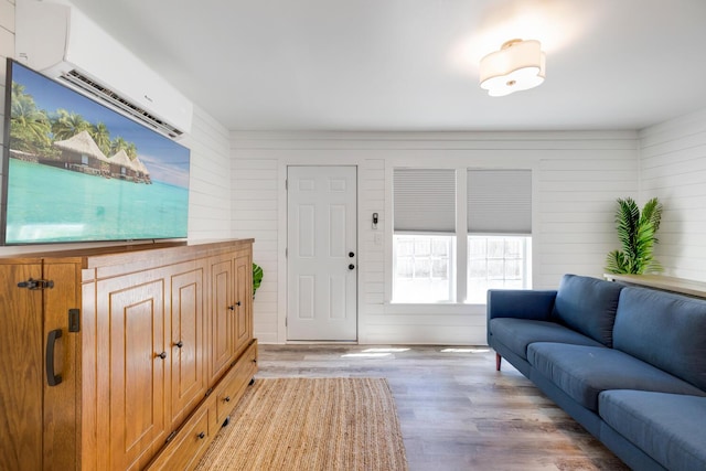 living room featuring light wood-type flooring, an AC wall unit, and wood walls