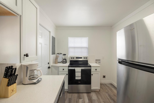 kitchen featuring appliances with stainless steel finishes, electric panel, white cabinetry, and crown molding