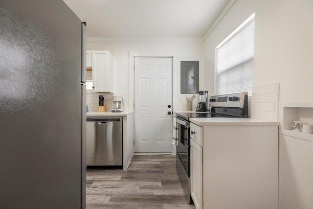 kitchen with electric panel, white cabinets, hardwood / wood-style flooring, decorative backsplash, and stainless steel appliances