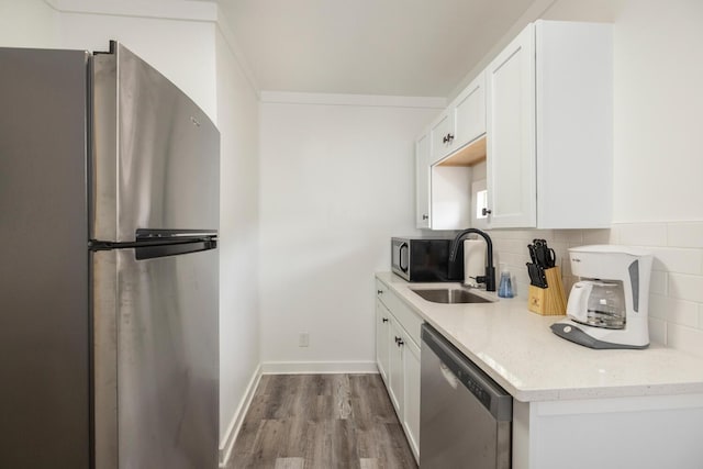 kitchen with sink, decorative backsplash, light stone counters, white cabinetry, and stainless steel appliances