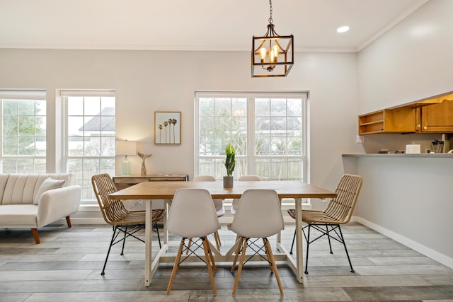 dining area with a wealth of natural light, crown molding, light hardwood / wood-style flooring, and a chandelier