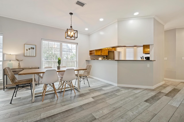 dining area with light hardwood / wood-style floors, crown molding, and a chandelier