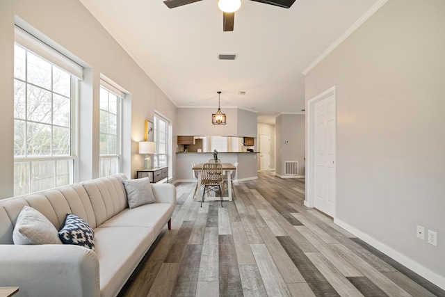 living room featuring ceiling fan with notable chandelier, light hardwood / wood-style floors, and ornamental molding