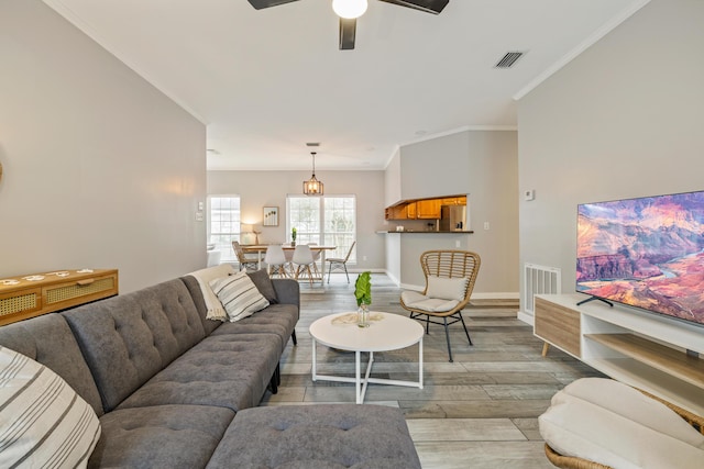 living room with light hardwood / wood-style floors, ceiling fan, and crown molding