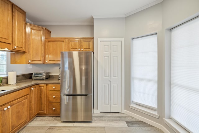 kitchen featuring stainless steel fridge, dark stone counters, and crown molding