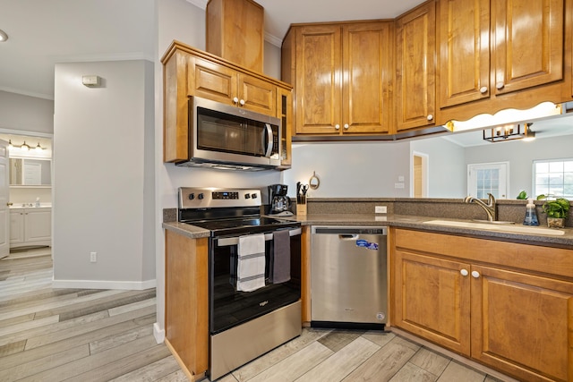 kitchen featuring crown molding, sink, light hardwood / wood-style flooring, and appliances with stainless steel finishes