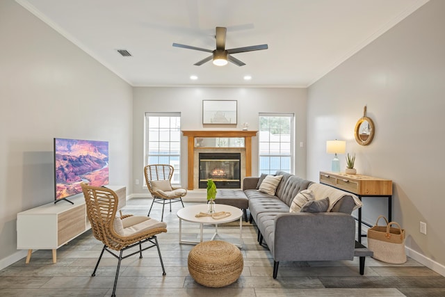 living room with ceiling fan, crown molding, and a fireplace