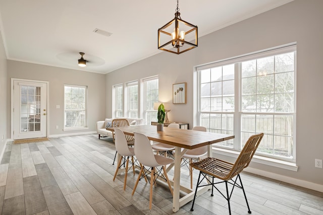 dining area with ceiling fan with notable chandelier, light hardwood / wood-style flooring, a healthy amount of sunlight, and crown molding