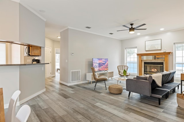 living room with ceiling fan, a healthy amount of sunlight, a tile fireplace, and light hardwood / wood-style flooring