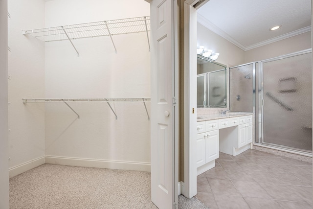 bathroom featuring vanity, a shower with shower door, and ornamental molding