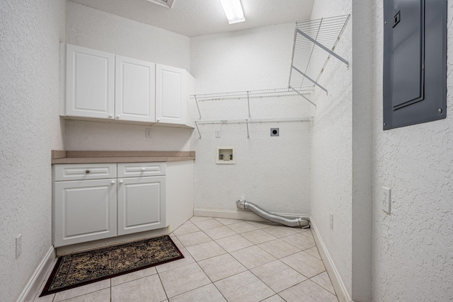 laundry area with cabinets, hookup for a washing machine, a textured ceiling, electric dryer hookup, and light tile patterned floors