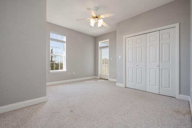 unfurnished bedroom featuring multiple windows, a closet, light colored carpet, and ceiling fan