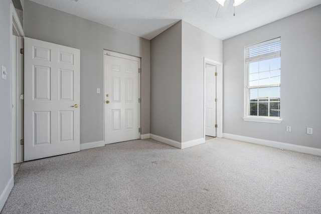 unfurnished room with light carpet, ceiling fan, and a textured ceiling