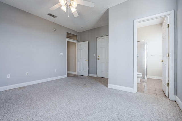 unfurnished bedroom featuring ceiling fan, ensuite bathroom, light colored carpet, and a textured ceiling