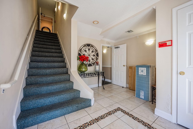 tiled foyer entrance with crown molding