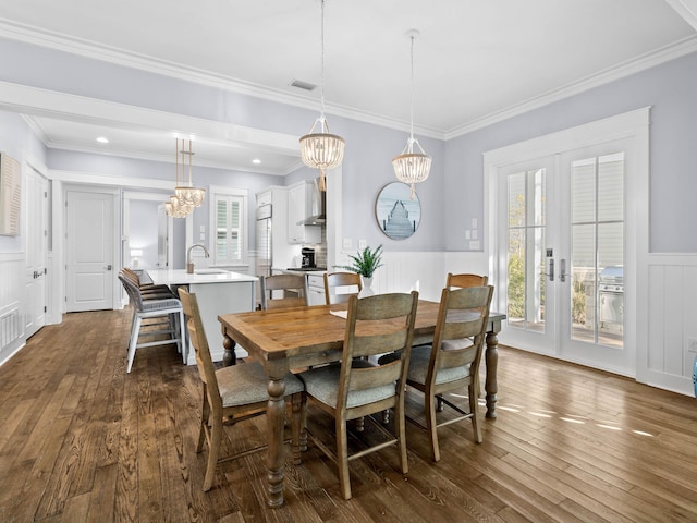 dining area with french doors, an inviting chandelier, ornamental molding, and sink