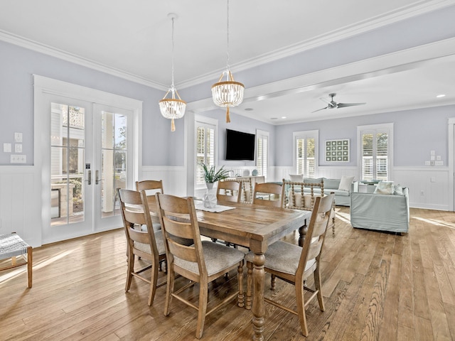 dining space with ceiling fan with notable chandelier, light wood-type flooring, ornamental molding, and french doors