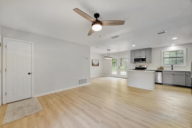 kitchen with gray cabinetry, a textured ceiling, light hardwood / wood-style flooring, pendant lighting, and stainless steel appliances