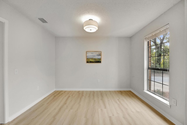 spare room with a textured ceiling and light wood-type flooring