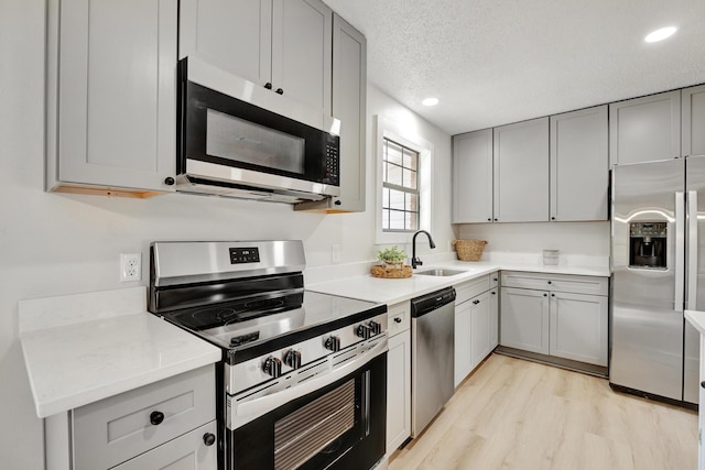 kitchen with gray cabinets, appliances with stainless steel finishes, sink, and a textured ceiling