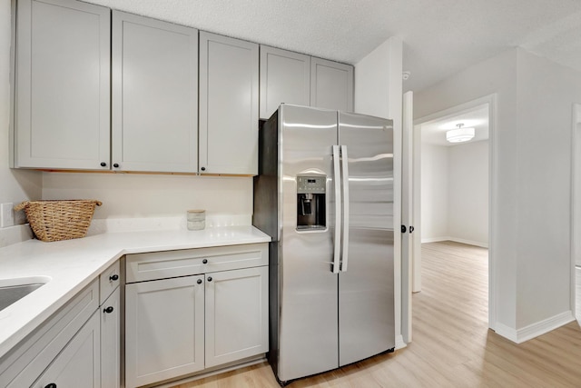 kitchen featuring stainless steel refrigerator with ice dispenser, gray cabinetry, a textured ceiling, and light hardwood / wood-style flooring