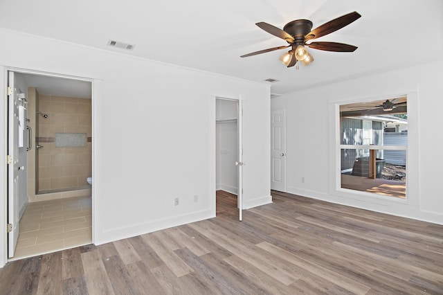 unfurnished bedroom with ensuite bathroom, ceiling fan, a spacious closet, light hardwood / wood-style floors, and a closet