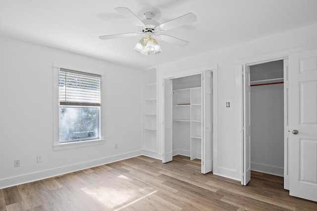 unfurnished bedroom with ceiling fan, two closets, and light wood-type flooring