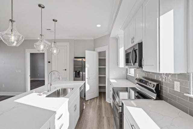 kitchen featuring stainless steel appliances, a sink, white cabinetry, ornamental molding, and tasteful backsplash