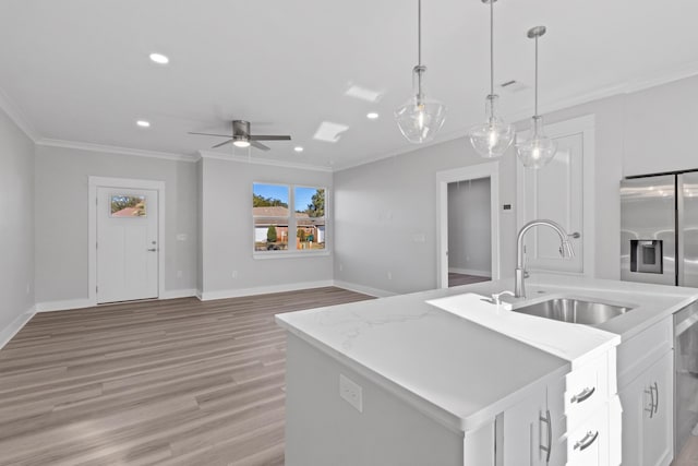 kitchen with ceiling fan, sink, a center island with sink, white cabinets, and hanging light fixtures